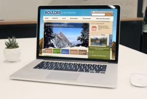 Laptop on a white desk showing the City of Boulder website.